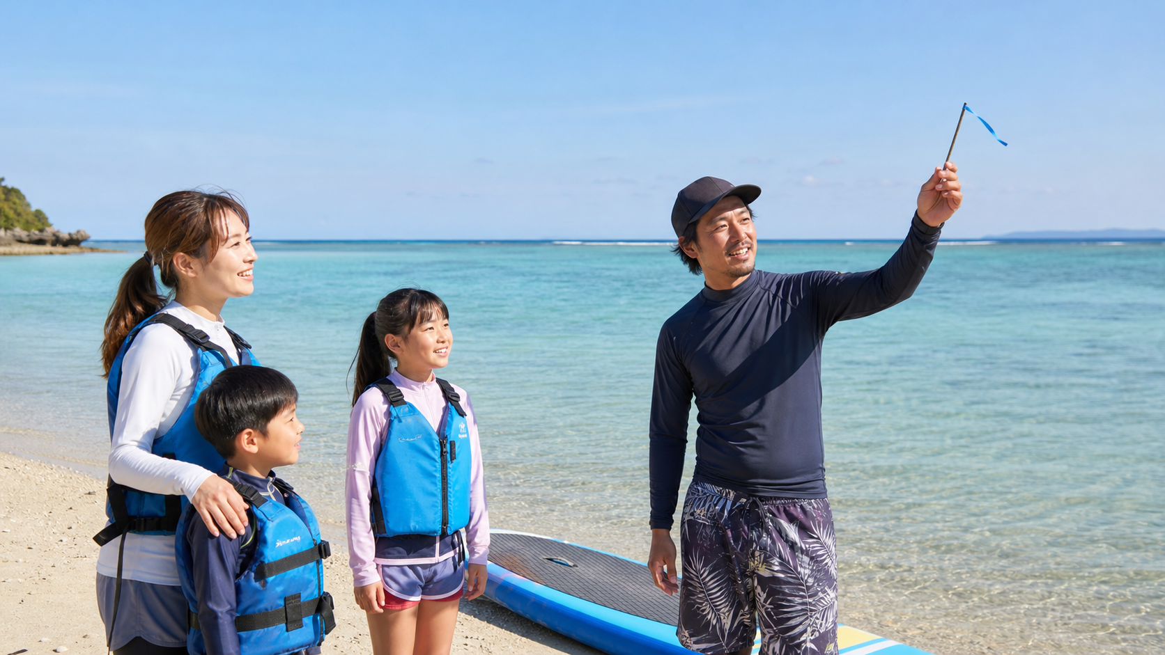 沖縄の海辺でガイドが風向きと海況を確認しながら家族に説明している様子