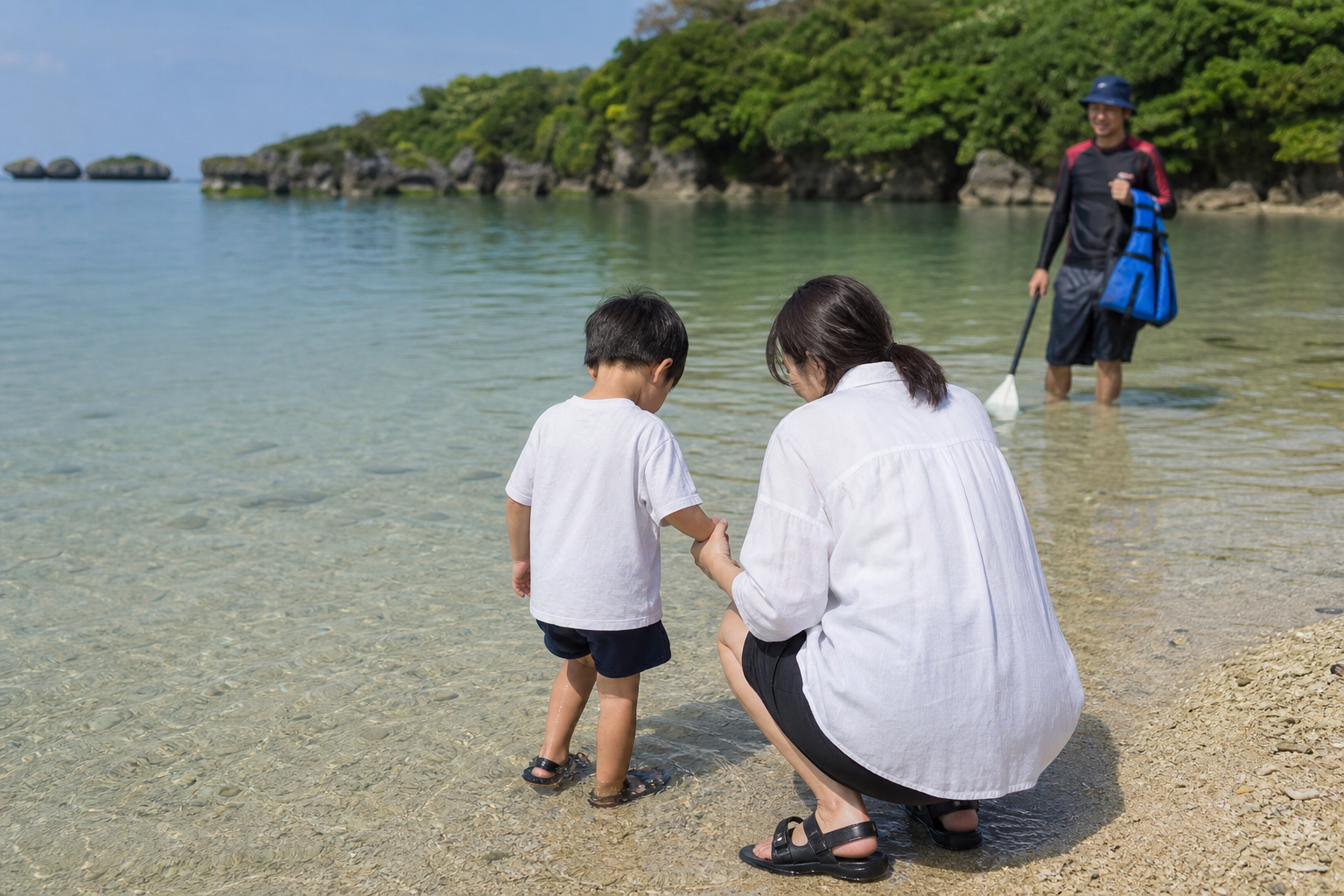 沖縄の浅瀬で親が子どもの手を取り、初めての海に少しずつ慣れている様子